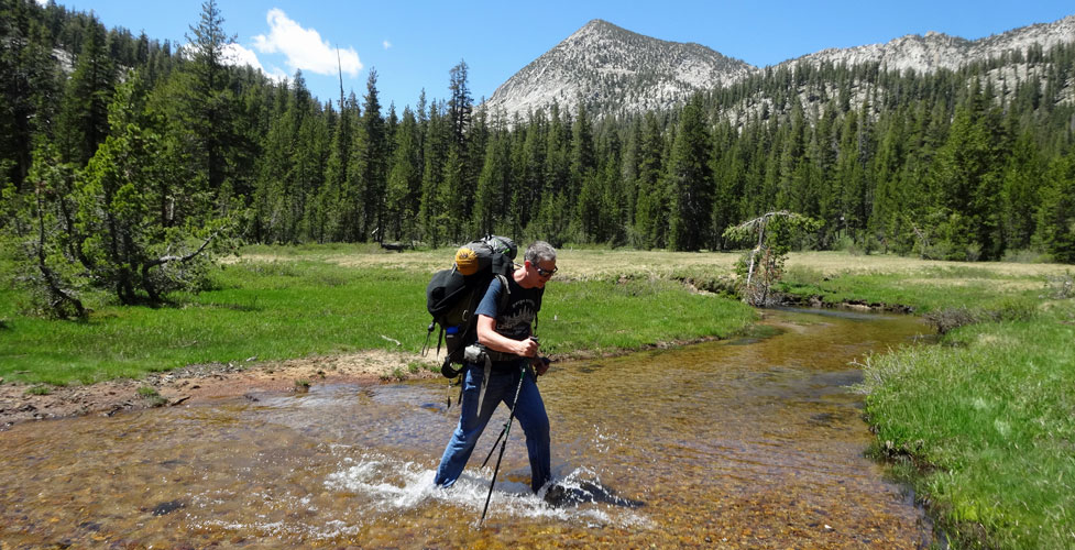 backpacker crossing stream